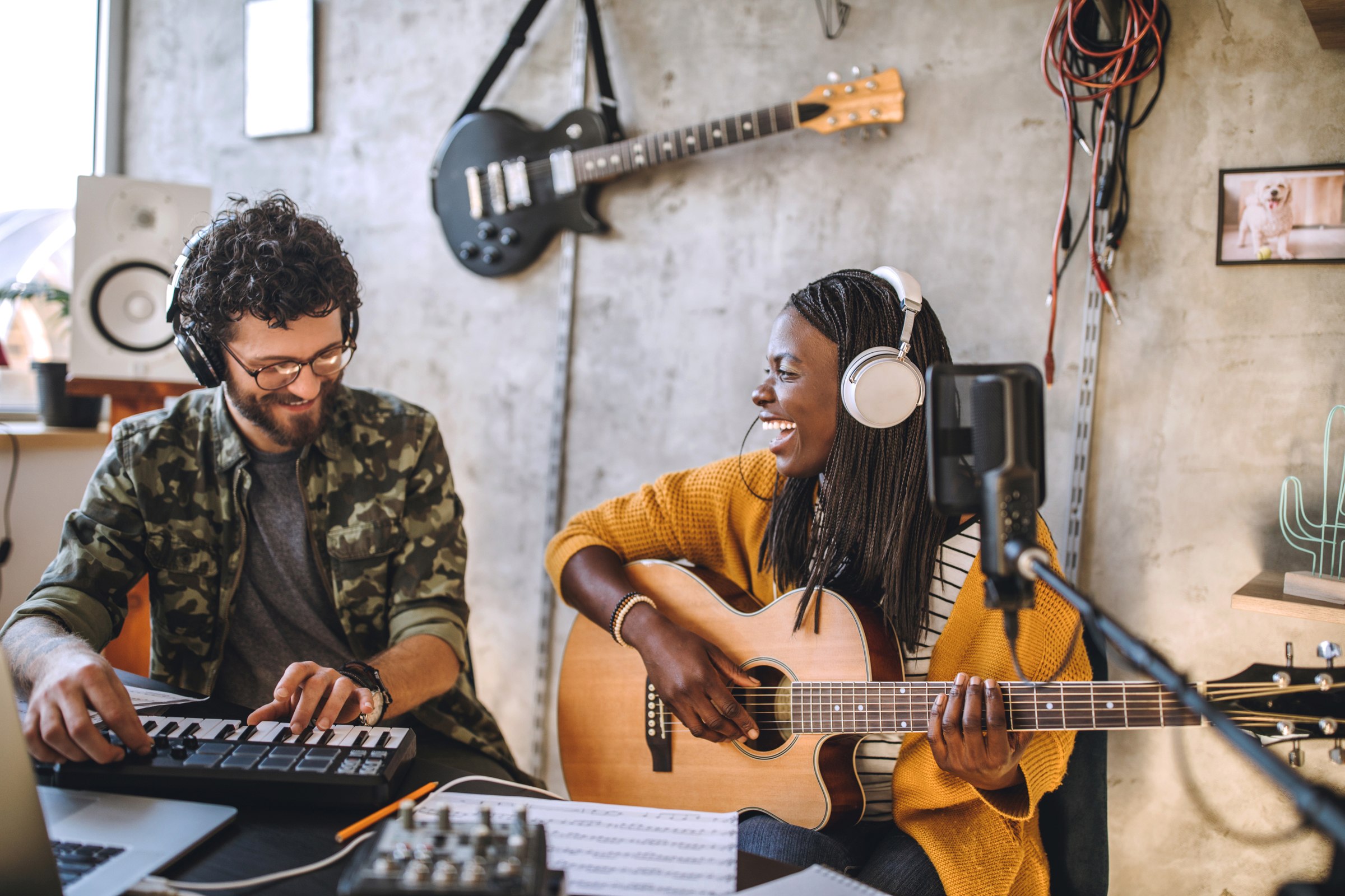Happy, young couple smiling lively while recording music at home